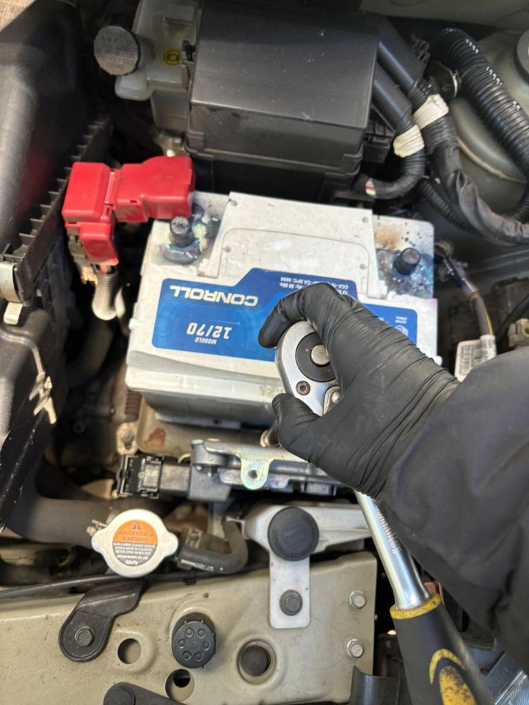 Técnico colocando una batería con llave y guantes